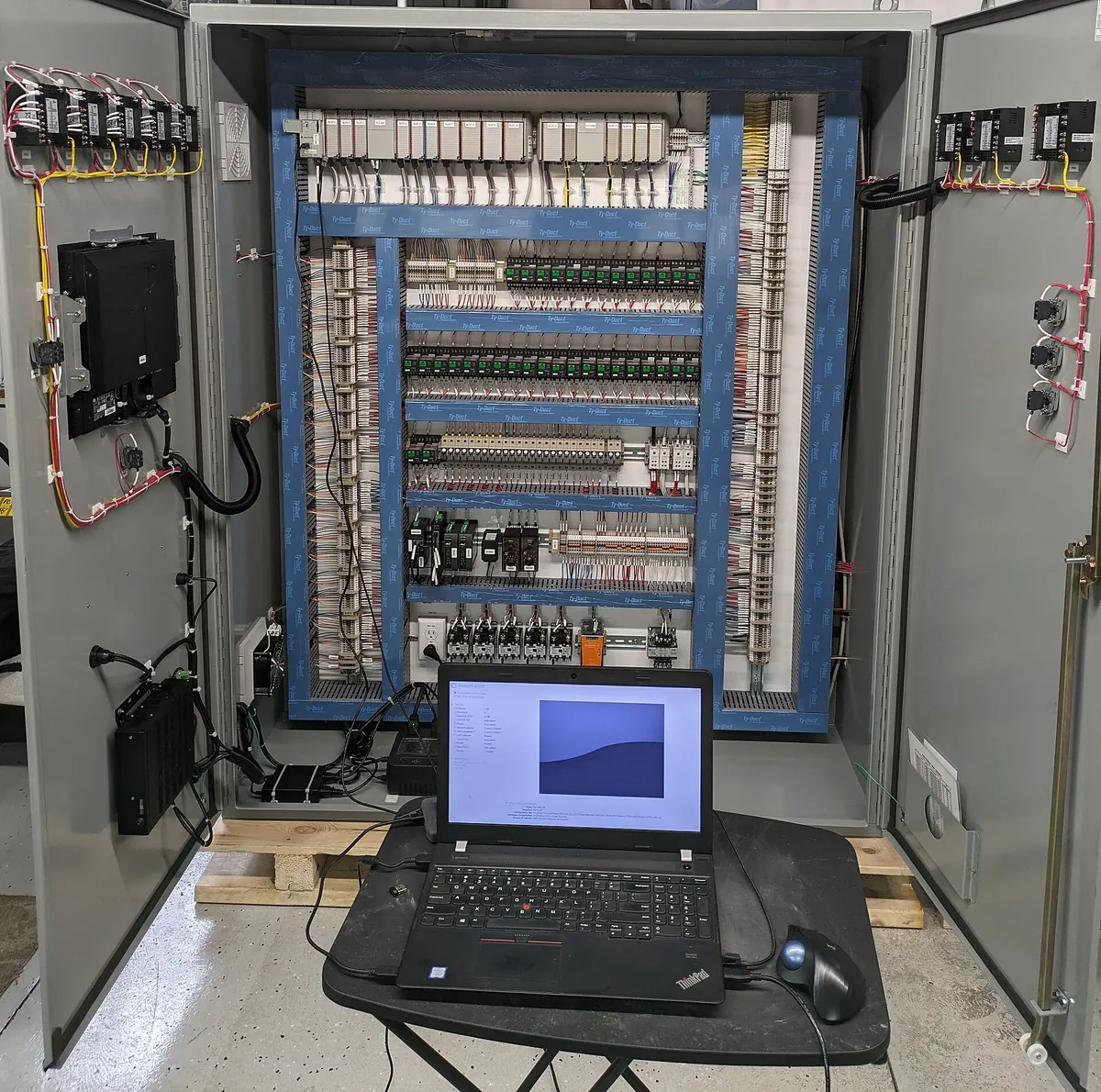 An electrical control panel being tested and commissioned with a laptop